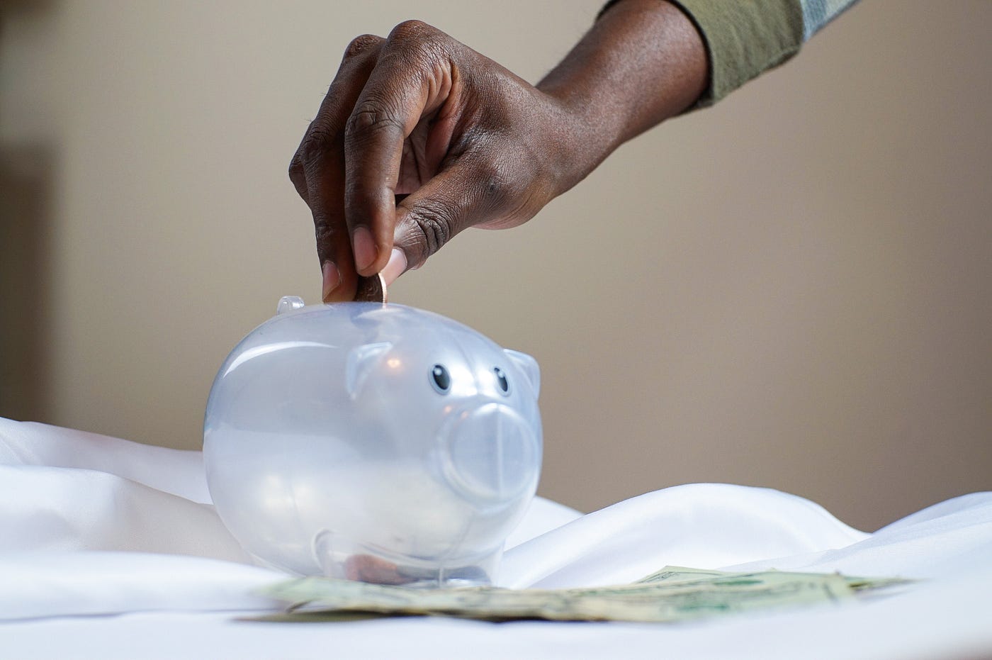 Person putting a coin in a piggy bank